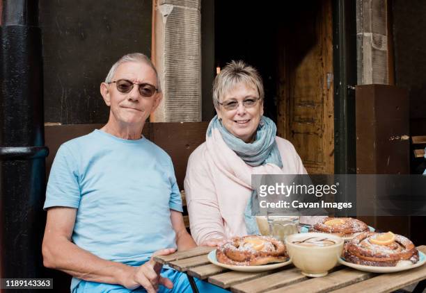 portrait of older couple sat at a cafe eating whilst travelling - older couple travelling photos et images de collection