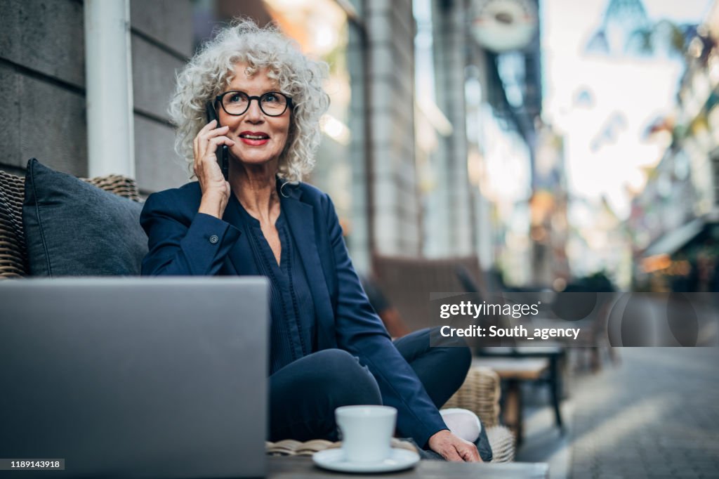 Senior Lady praten op mobiel buitenshuis in café
