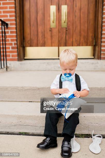 toddler ring bearer with pacifier sits on steps of church - baby accessories the dummy stock pictures, royalty-free photos & images