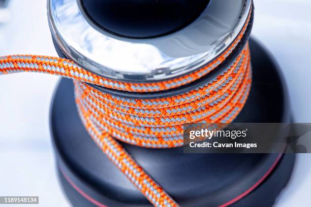 orange rope wrapped around a winch on the deck of a cruising catamaran - kabelwinden stock-fotos und bilder