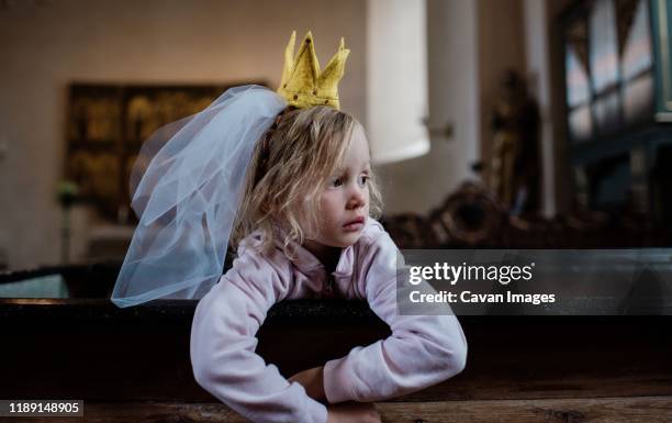 girl sat with a dress up crown & veil on her head, looking thoughtful - small wedding stock pictures, royalty-free photos & images