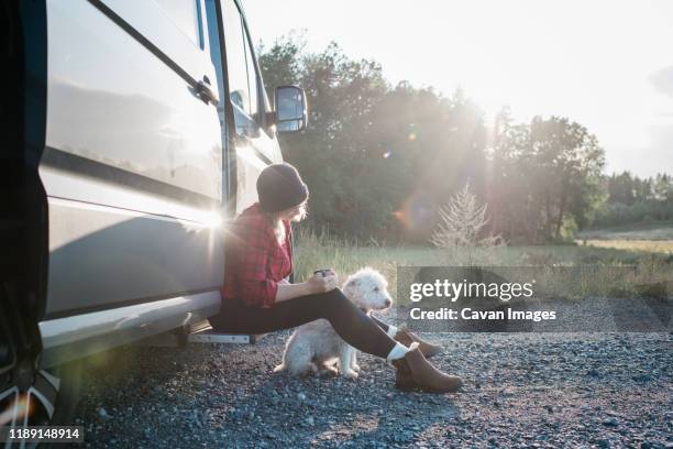 woman drinking coffee whilst camping in a camper van with her dog - portrait of a camper stock pictures, royalty-free photos & images