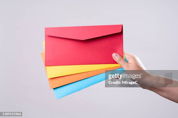 hand holding four colored envelopes - quatre objets photos et images de collection