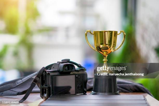 golden trophy and camera on a green background - competitions and contests stock pictures, royalty-free photos & images