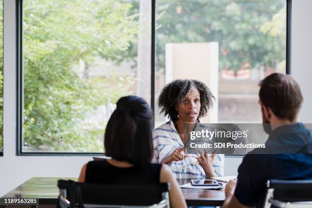 serious female mental health professional talks with couple - married doctors stock pictures, royalty-free photos & images