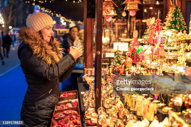 choosing a gift at a christmas market stall - woman picking up toys stock pictures, royalty-free photos & images