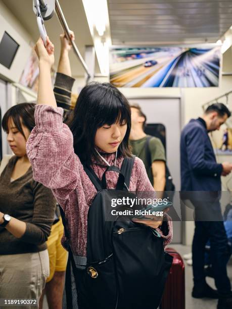 jonge vrouw op een drukke japanse metro trein - crowded train station smartphone stockfoto's en -beelden