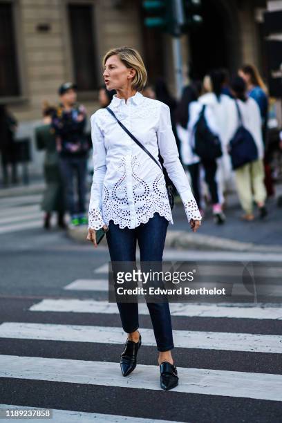 Guest wears a white broderie anglaise shirt, navy blue denim pants, pointy flat shoes, outside the Bottega Veneta show during Milan Fashion Week...