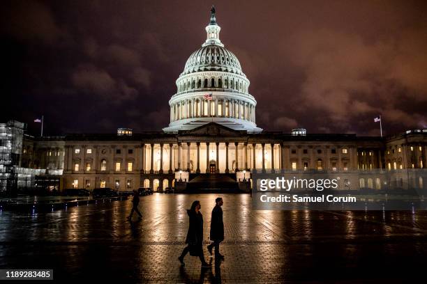 People walk along the east front plaza of the US Capitol as night falls on December 17, 2019 in Washington, DC. The House Rules Committee is holding...