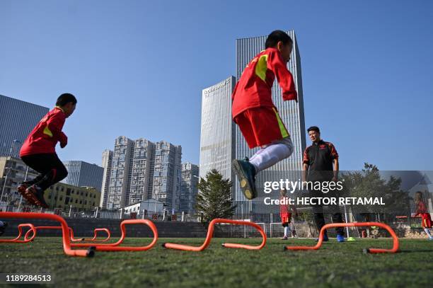 This photo taken on December 10, 2019 shows former Manchester United and Chinese international footballer Dong Fangzhuo watching as children train,...