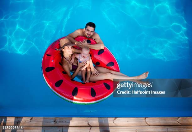 top view portrait of young couple with toddler girl in swimming pool outdoors at home. - baby schwimmen stock-fotos und bilder