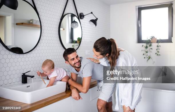 portrait of young couple with toddler girl washing indoors in bathroom at home. - man washing his teeth stock-fotos und bilder