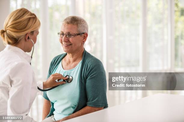 médico que usa estetoscopio mientras examina al paciente - heart disease fotografías e imágenes de stock