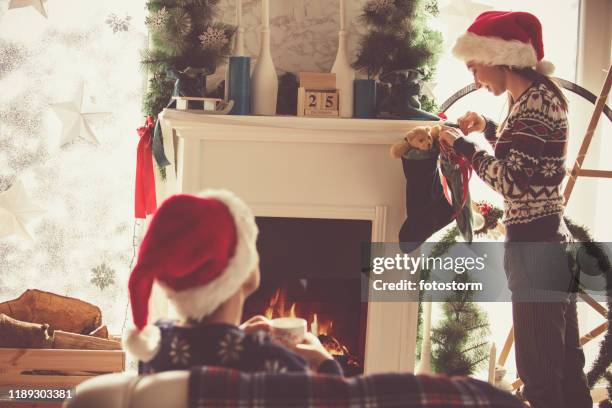 moeder en dochter in santa's hoeden genieten van kerstdag - kousen stockfoto's en -beelden