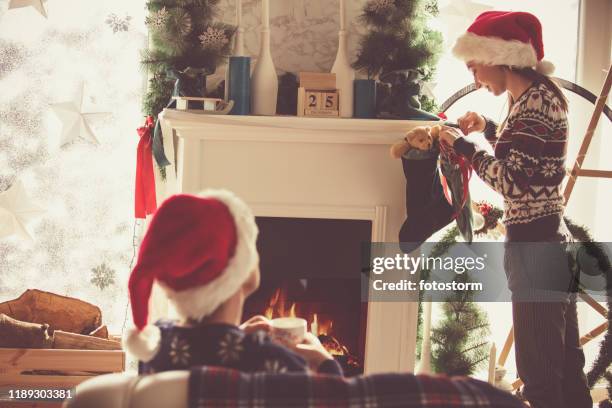 mother and daughter in santa's hats enjoying christmas day - stocking tops stock pictures, royalty-free photos & images