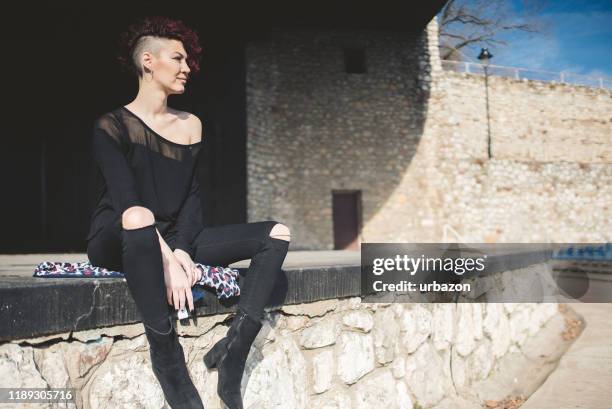 modern and attractive girl with red hair sitting on the edge on an empty stage and enjoys in beautiful day outdoor. - girl sitting with legs open stock pictures, royalty-free photos & images