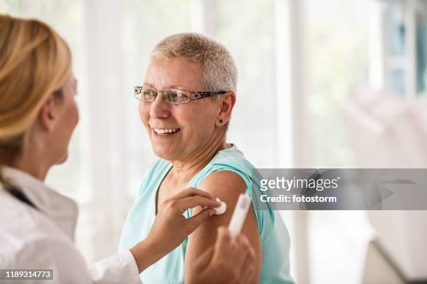 ワクチン接種前に患者の腕を消毒する医師 - インフルエンザワクチン ストックフォトと画像