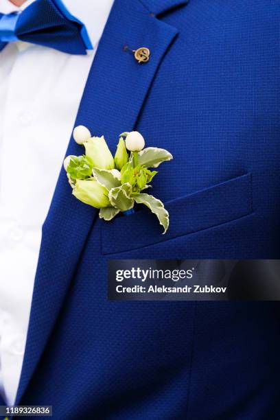 a young man or groom in a white shirt, bow tie and blue vest or jacket. beautiful boutonniere of white roses and green leaves in a vest pocket or lapel. wedding theme. - revers stock-fotos und bilder