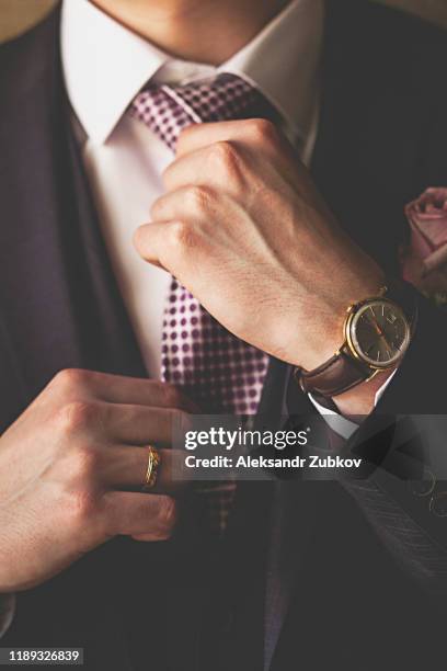 men's hands adjust the tie close-up. a successful young man who is a businessman, entrepreneur, expensive watches, simply fashion classic suit. blurred background. - orologio di lusso foto e immagini stock