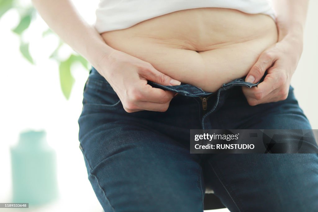 Overweight woman buttoning tight jeans