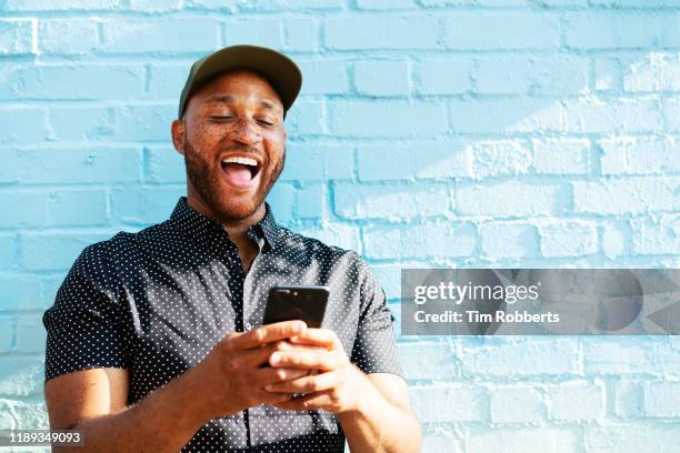 man laughing with smart phone - boa notícia imagens e fotografias de stock