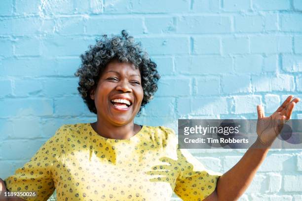 happy woman laughing with arms up - cheeky expression stock-fotos und bilder