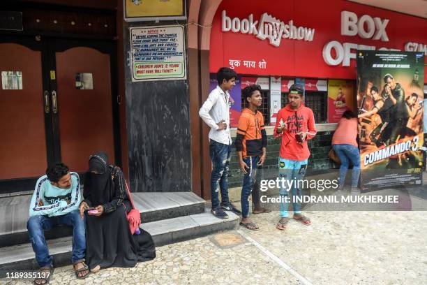 In this photograph taken on December 1 people wait to enter a cinema in Mumbai. - As a prolonged economic slowdown forces Indians to curb spending on...