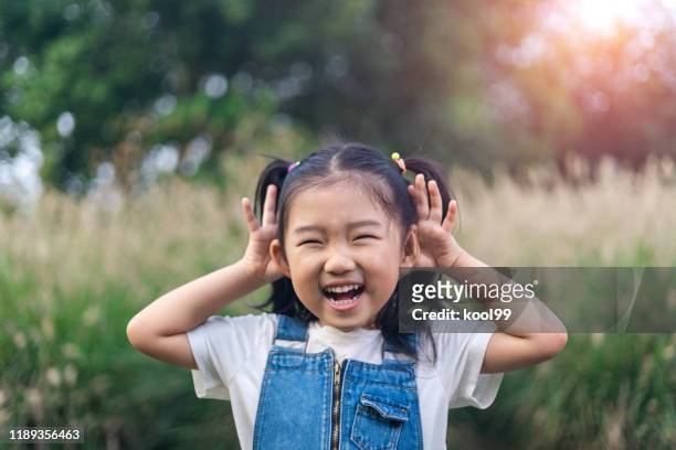 klein meisje spelen spelletjes - ear stockfoto's en -beelden