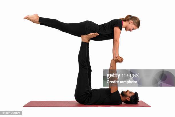 young adult couple practicing acroyoga front plank pose - trainer cutout stockfoto's en -beelden