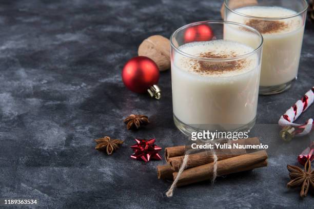 fresh eggnog with cinnamon with christmas decorations on dark background. copy space, low key. - eggnog stock pictures, royalty-free photos & images