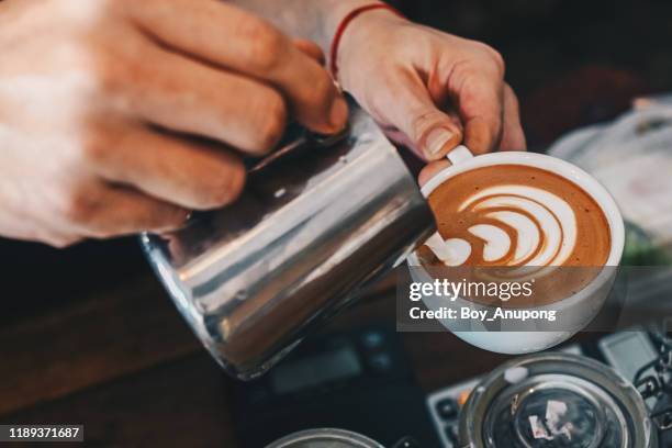 barista pouring steamed milk to hot coffee to making latte art. - soft drink stock-fotos und bilder