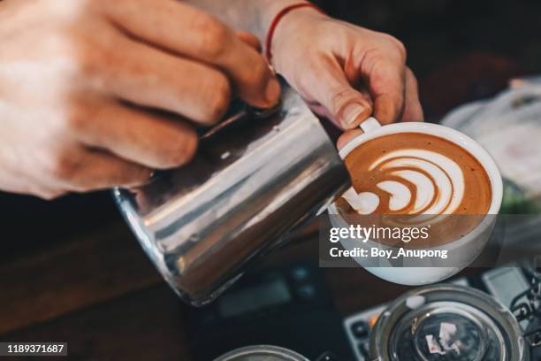 barista pouring steamed milk to hot coffee to making latte art. - espresso maker fotografías e imágenes de stock