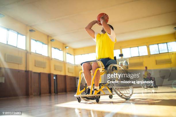 paraplegic man taking a shot at basketball court - wheelchair basketball team stock pictures, royalty-free photos & images