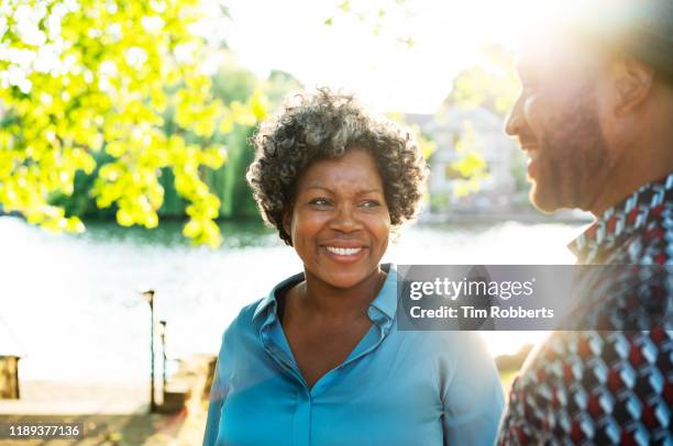 woman and man smiling together next to river - chatting park stockfoto's en -beelden