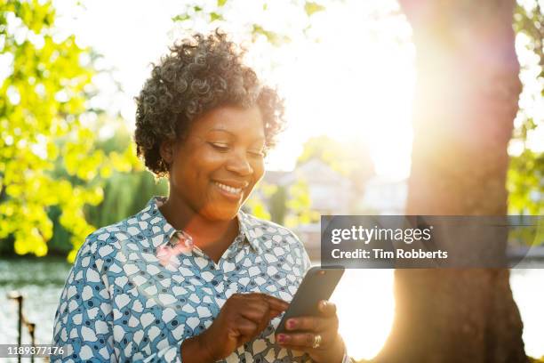 smiling woman with smart phone outside - fashion in an age of technology costume institute gala stockfoto's en -beelden