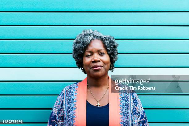 portrait of woman against blue wall - baby boomer stock pictures, royalty-free photos & images