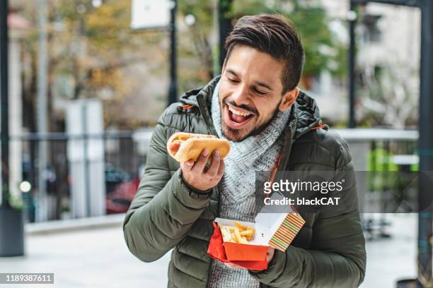 portrait of young man eating hot dog - asian eating hotdog stock pictures, royalty-free photos & images