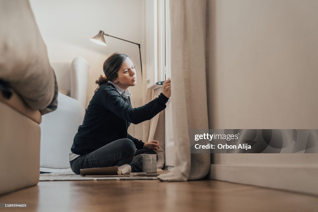 Mujer embarazada pintando ventanas en blanco