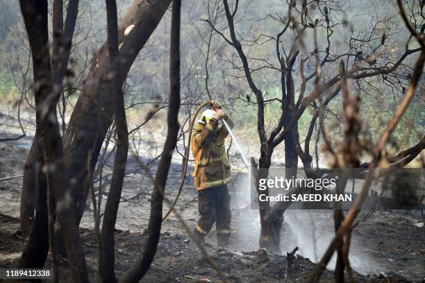 Firefighter doses a bushfire in Dargan, some 130 kilometres northwest of Sydney on December 18, 2019. - Australia this week experienced its hottest...