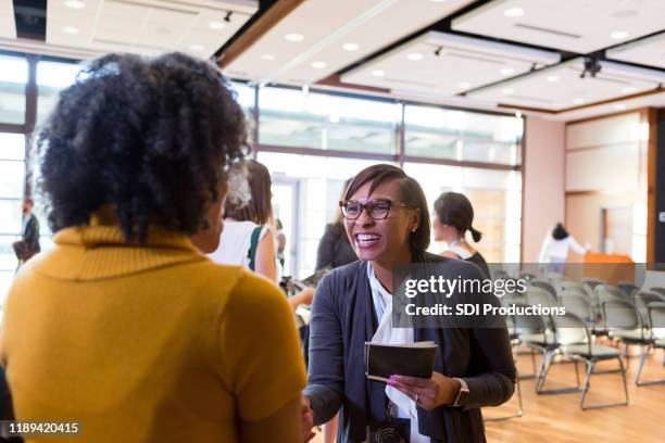 cheerful conference volunteer passes out programs - town hall meeting stock pictures, royalty-free photos & images