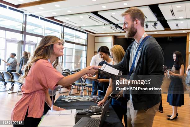 businesswoman reviews conference schedule with colleague - exhibition stock pictures, royalty-free photos & images