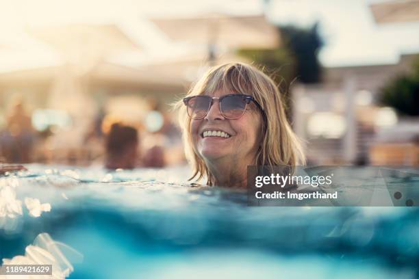 portret van een gelukkige senior vrouw genieten van zwembad - happy old women stockfoto's en -beelden