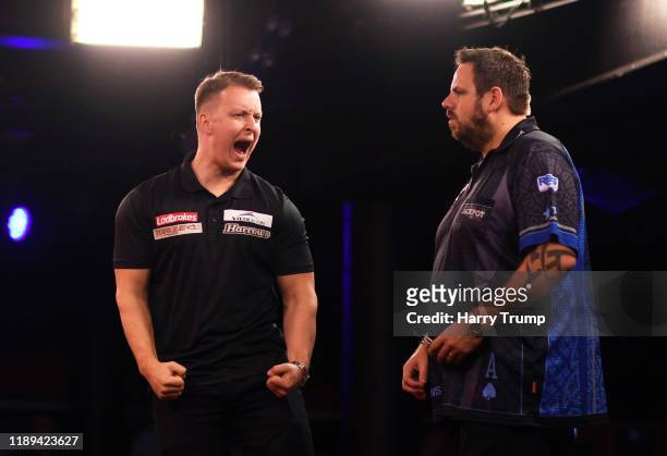 Josh Payne celebrates after winning a leg as Adrian Lewis looks on during Day One of the PDC Players Darts Championship at Butlins Resort on November...