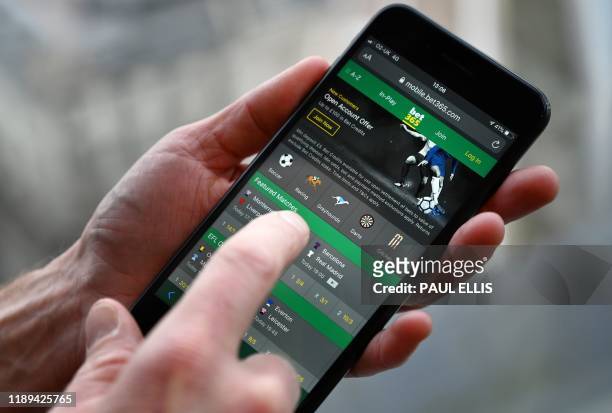 Man poses for a photograph with the online gambling website Bet365 displayed on a smartphone, in London on December 18, 2019. - Denise Coates, chief...