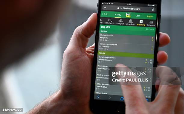 Man poses for a photograph with the online gambling website Bet365 displayed on a smartphone, in London on December 18, 2019. - Denise Coates, chief...