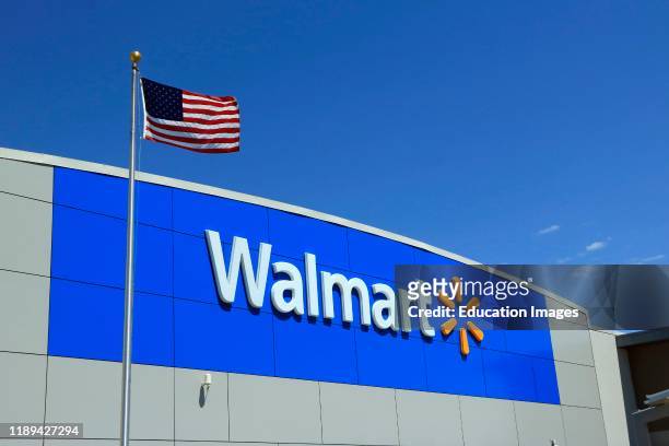 Wal-Mart logo on the store front of a store with American flag flying in front.
