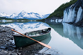 Canoe resting on rock covered ice of Valdez Glacier with icebergs behind. Valdez, Alaska.