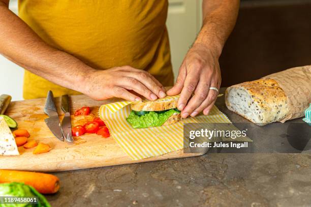 man wrapping a sandwich in the kitchen - beeswax stock pictures, royalty-free photos & images