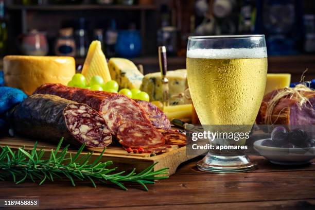 tapas of cheese, cured ham, salami, beer and chorizo on a rustic wooden table - tapas stock pictures, royalty-free photos & images