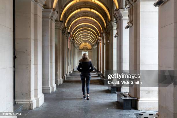 single women walking down the center of a column walkway - column building stock pictures, royalty-free photos & images